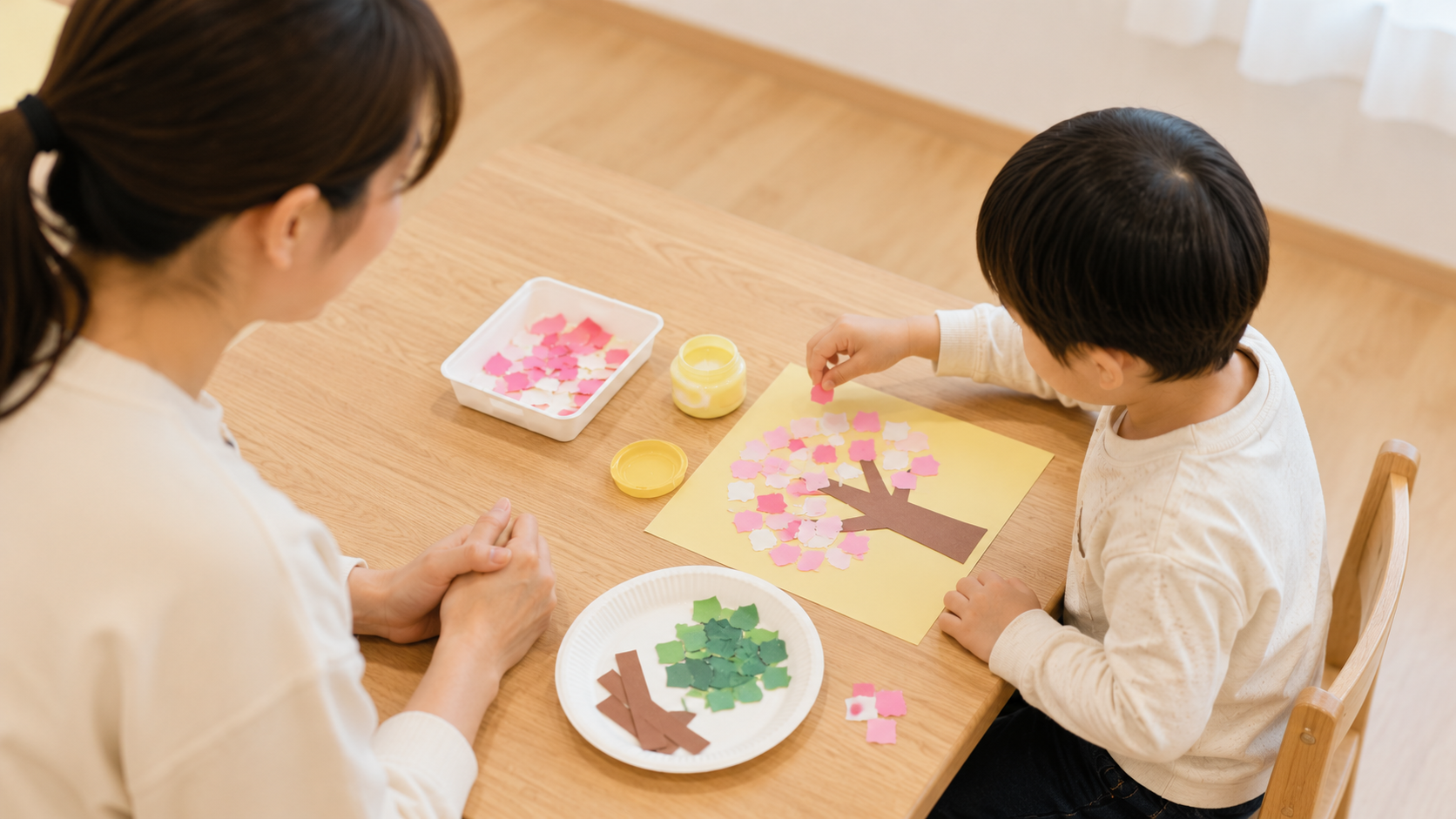 色紙を使って季節の木の制作に取り組む子どもと見守る支援員