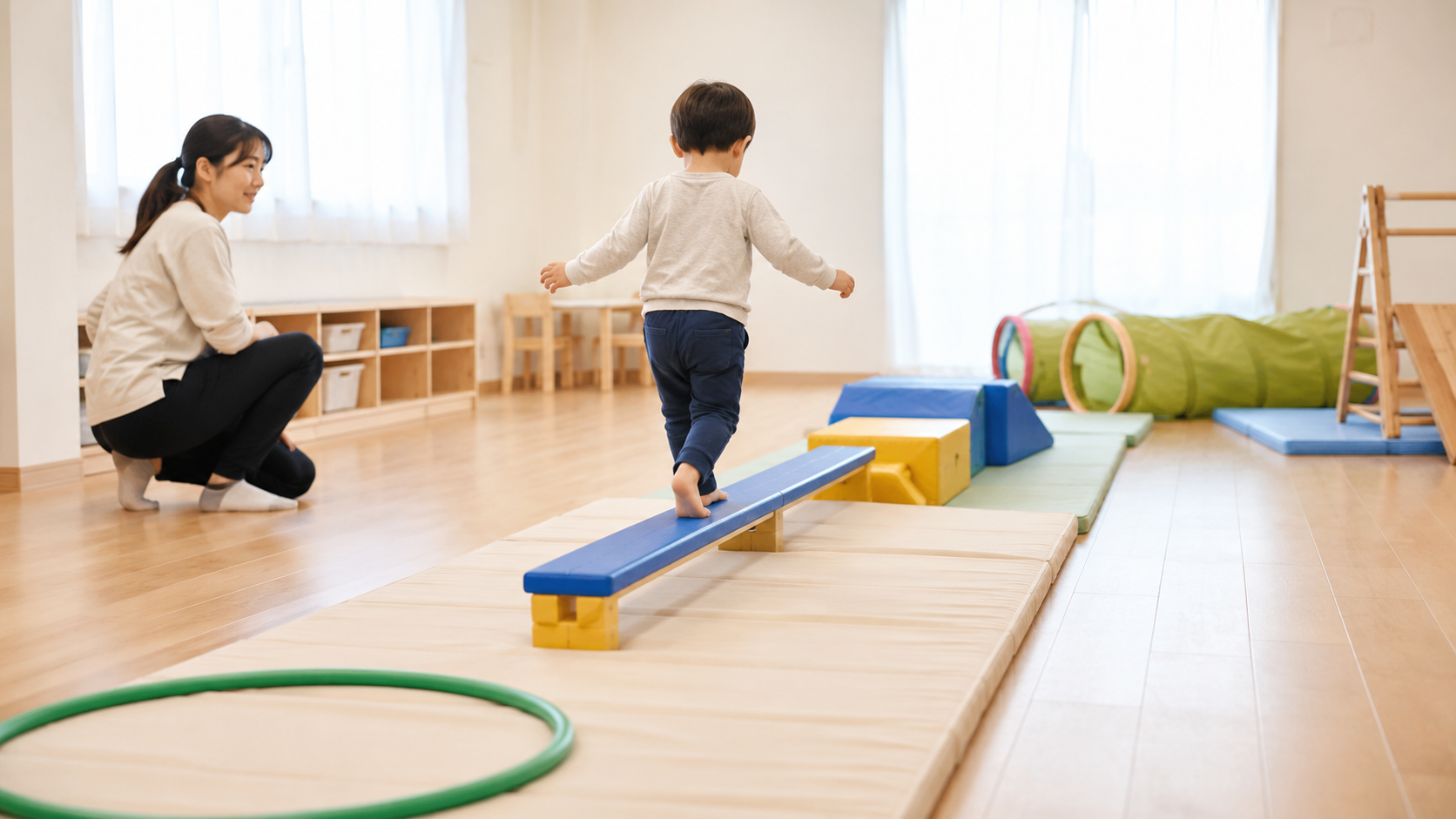 低い平均台を進む子どもを斜め後ろから見守る支援員